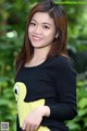 A woman in a black sweater holding a yellow stuffed animal.