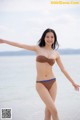 A woman in a brown bikini standing on a beach.