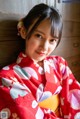 A woman in a red kimono sitting on a wooden bench.