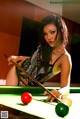 A woman leaning over a pool table holding a cue.
