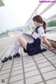 A woman in a school uniform sitting on a bridge.