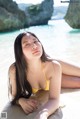 A woman in a yellow bikini laying on the beach.