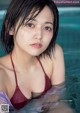 A woman in a red bikini sitting in a pool.