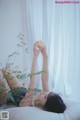 A woman laying on a bed holding an orange.