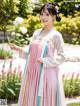 A woman in a pink and blue hanbok is posing for a picture.