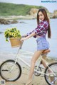 A woman riding a bike with a basket full of flowers.