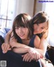 A couple of young women sitting on top of a couch.