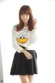 A woman in a white sweater and black skirt posing for a picture.