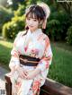 A woman in a kimono sitting on a wooden bench.