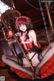 A woman in a red and black lingerie sitting on a swing.