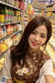 A woman in a brown dress standing in front of a shelf of food.