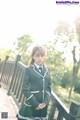 A woman in a school uniform standing on a bridge.