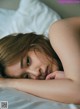 A woman laying on a bed with her head on her hands.