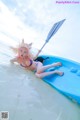 A woman in a bikini laying on a blue kayak in the water.