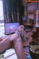 A naked woman sitting in front of a computer with a cat on her back.