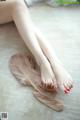 A woman with red nail polish sitting on the floor.