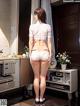 A woman in a white shirt and white shorts standing in a kitchen.