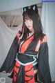 A woman in a black and red kimono with a cat ears headband.