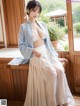 A woman in a blue and white kimono sitting on a window sill.