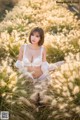 A woman sitting in a field of tall grass.