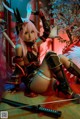A woman with pink hair sitting on the ground with a sword.