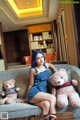 A woman sitting on a couch with two teddy bears.