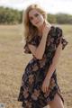 A woman in a floral dress posing in a field.